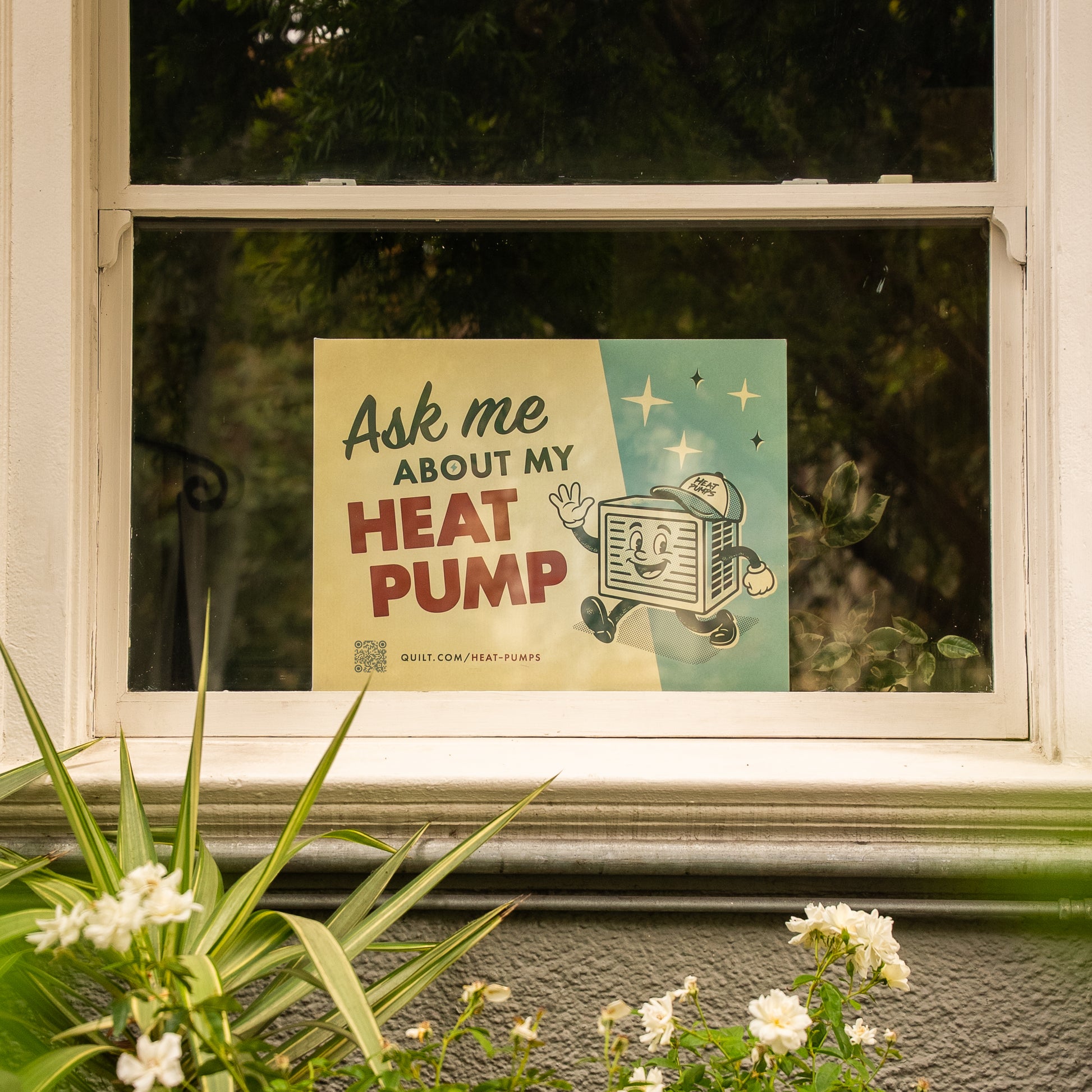 Window with a poster advertising heat pumps, surrounded by plants and flowers.