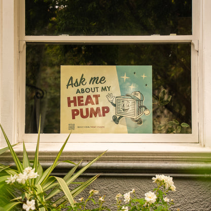 Window with a poster advertising heat pumps, surrounded by plants and flowers.