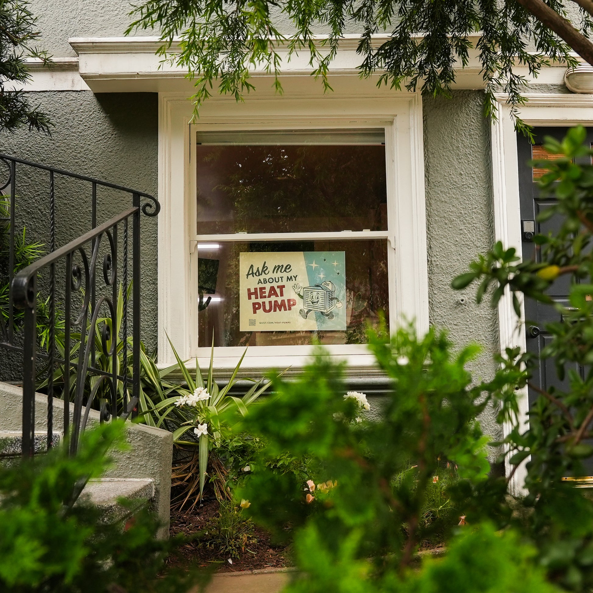 Window with a sign asking 'Ask me about my heat pump' on a house exterior.