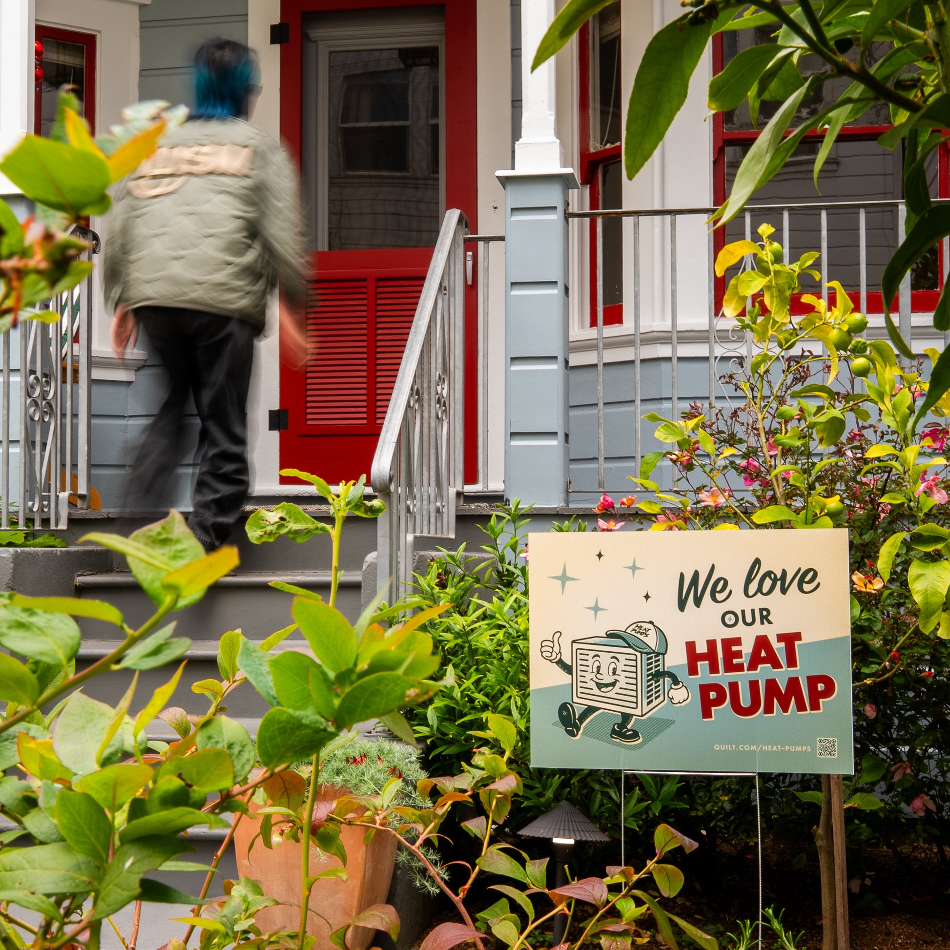 Person walking up a set of stairs to a house with a sign about love for a heat pump in the foreground.
