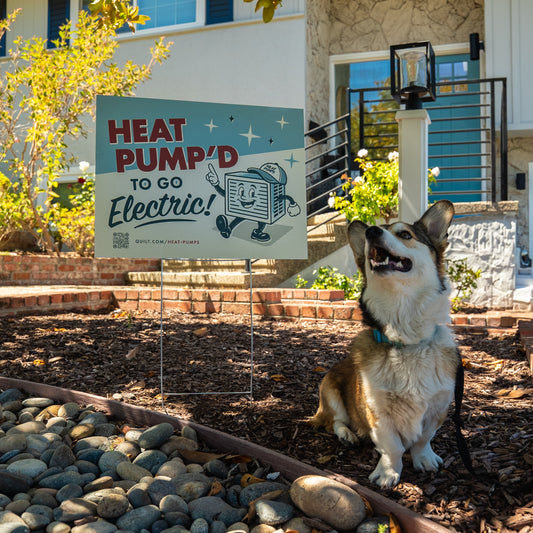 Dog sitting next to a 'Heat Pump'd to Go Electric' sign in front of a house.