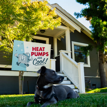 Dog lying on grass in front of a house with a 'Heat Pumps Are Cool!' sign.