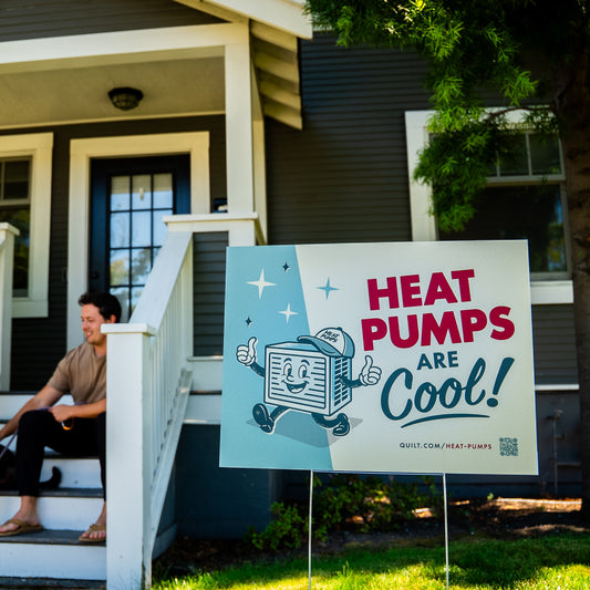 Person sitting on a house porch with a 'Heat Pumps Are Cool!' sign in front.